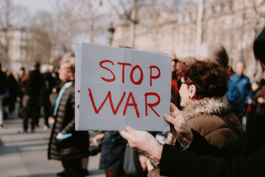 Image of a protest with the sign “STOP WAR”, depicting how Singapore interest rates and inflation are affected by global factors such as war